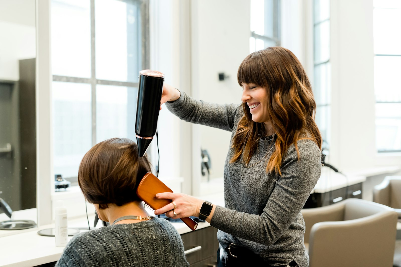 Friseurin föhnt einer Kundin die Haare